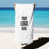 custom_merch_goods_rest_30_04_06_2026 White beach towel with custom logo on sandy beach