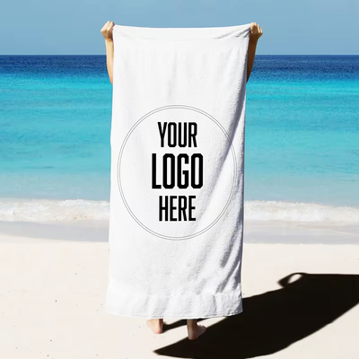 White beach towel with custom logo on sandy beach